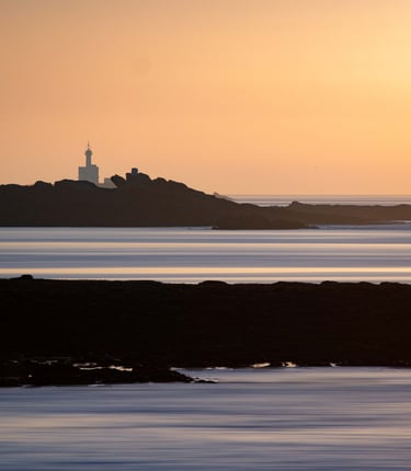 a lighthouse at sunset with a lighthouse in the background
