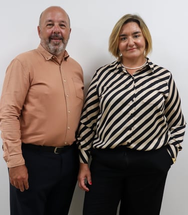 Professional portrait of male and female business partners standing together in formal attire against a white background.