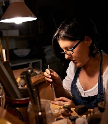 Joyera artesana elaborando joyas hechas a mano con herramientas profesionales en un taller.