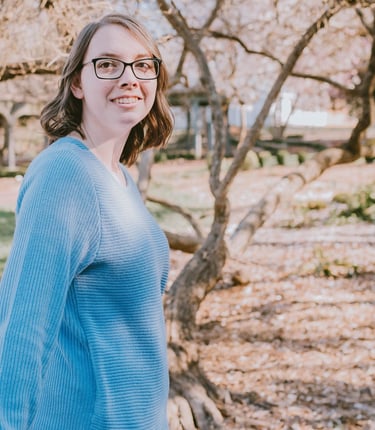 Kristin Gunner, doula, wearing glass and smiling as she looks back at the camera outside