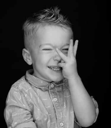 portret a young boy with a his fingers in to look between the eyes