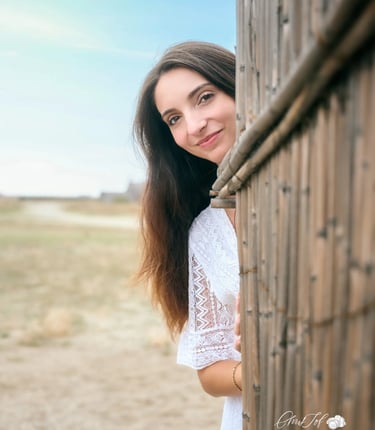 Portrait d'une femme brune souriante regardant derrière une maison de pecheur sur une plage à Canet.