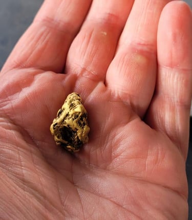 A hand holding a large gold nugget