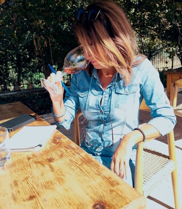 a french sommeliere sitting at a table with a glass of wine