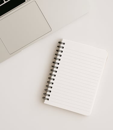 Minimalist home office setup with a silver laptop, open blank spiral notebook, and white desk for productivity and work.
