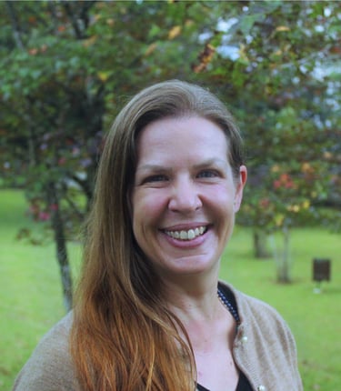 woman with red hair in front of trees