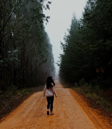 Brava Braun mindfully walking down a dirt road in the middle of a forest