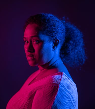 A woman's dramatic profile portrait with vibrant pink and blue neon lighting in a studio.