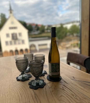 Eine Flasche Wein mit 4 Gläsern - im Hintergrund das alte Wernauer Rathaus