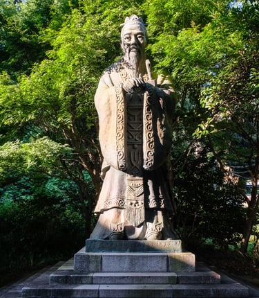 stone statue depicting Confucius in a forest