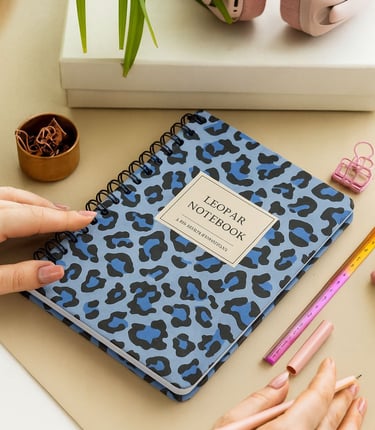 a woman's hand holding a notebook with a notebook and a pen