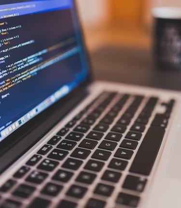 A tela de um laptop exibindo o código de um software de desenvolvimento web, com uma xícara de café