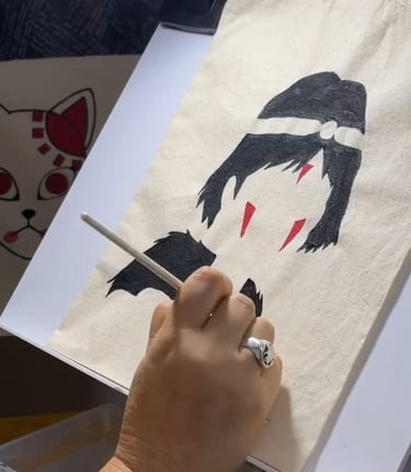 Artista pintando a mano un personaje de anime de La Princesa Mononoke sobre una tote bag de lino