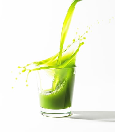Fresh green juice splashing into a clear glass against a white background.