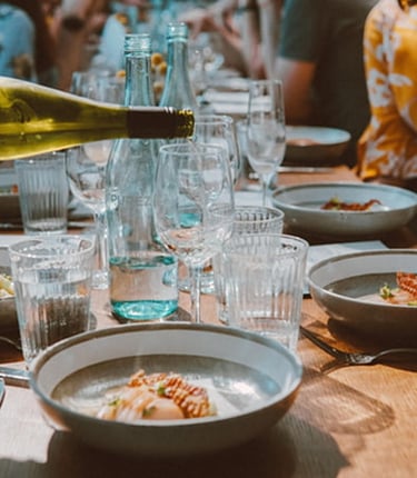 table avec plein de personnes avec un plat réalisé par un partenaire local et dégustation de vin 