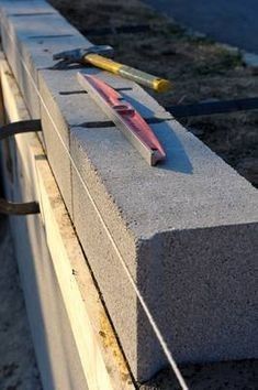 Pose de blocs de béton pour mur de soutènement ou cloison, avec cordeau de maçon, niveau à bulle et