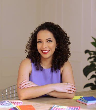 Mulher cacheada sorridente com braços cruzados, oferecendo serviços de coloração pessoal