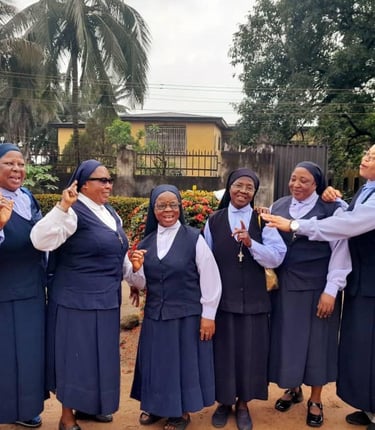 A group of cheerful Catholic nuns in blue and white habits smiling and socializing outdoors.