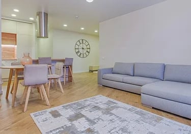 Modern open plan living room with a grey sectional sofa, dining set, and hardwood floors.