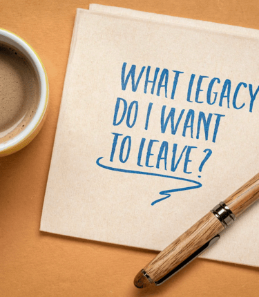 Notebook with message ‘What legacy do I want to leave?’ and coffee cup, symbolizing estate planning.