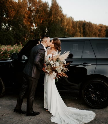Elegant black luxury SUV with a bride and groom sharing a romantic kiss, perfect for wedding transpo