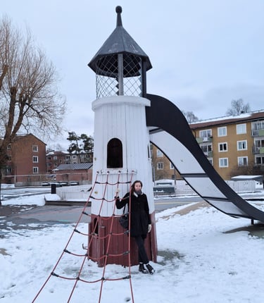 Bild på Mia framför en fyr på en lekplats. Snö på marken.