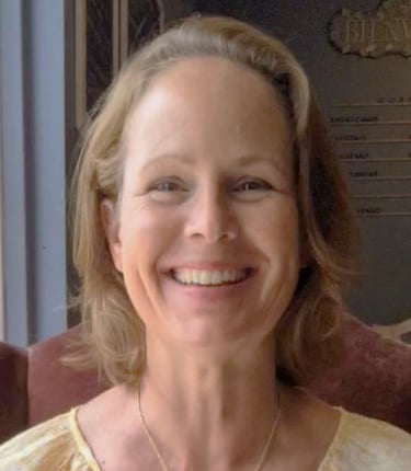 a woman in a yellow dress smiling and holding a cake