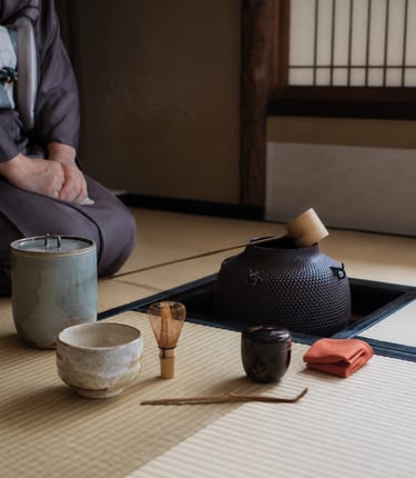 Traditional Japanese tea ceremony set with matcha whisk, bowl, and iron kettle on tatami mat.