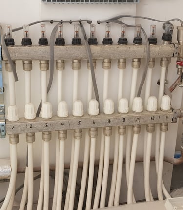 Verdeler voor centrale verwarming met witte leidingen en regelventielen – installatie in Leuven