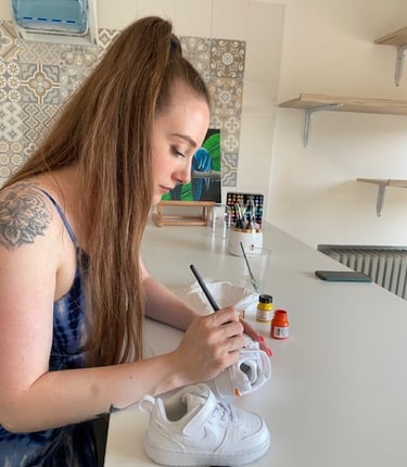 Ragazza di profilo che realizza custom fatte a mano su scarpe Nike bianche