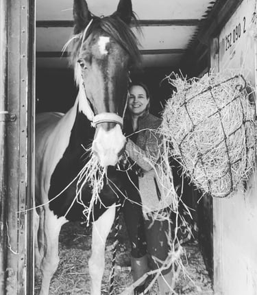 Jennifer en haar paard Fayah staan samen in de deuropening van de stal