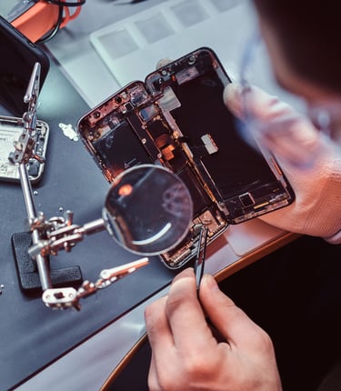 Técnico usando pinzas y lupa para la reparación  de celulares y el mantenimiento 