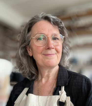 Ceramic artist Anna Butler looking to camera, in her North London ceramic studio