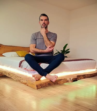 The founder of Axel Atelier sitting on a bespoke live edge floating bed, showcasing structural integ
