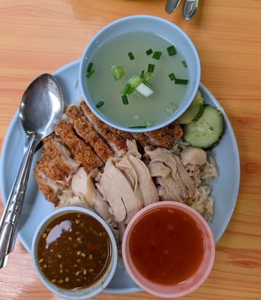 Thai Hainanese chicken rice plate with crispy fried chicken, steamed chicken, broth, and dipping sauces.