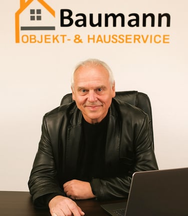 Seniorchef Herr Baumann von Baumann Objekt- & Hausservice sitzt am Schreibtisch 