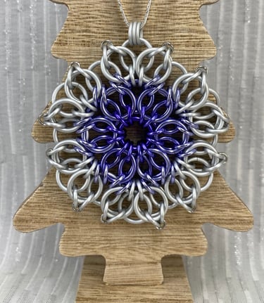 An ornament crafted from chainmaille. Purple and white.