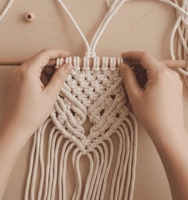 manos tejiendo con la ´tectica macramé, los hilos son de color crudo