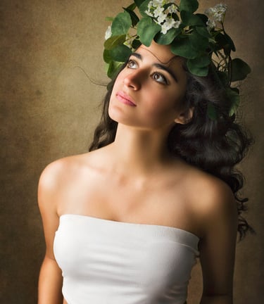 a gorgeous girl with long black curly hair looking up as the wind blows her hair away, she wears a vines crown with flowers