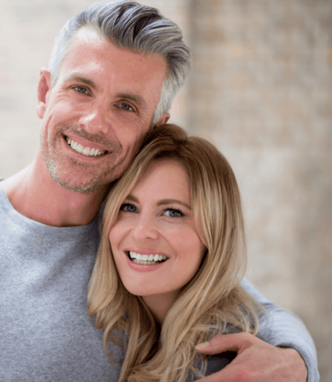 a man and woman smiling and hugging each other