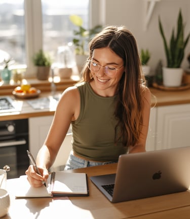a woman sitting at a table with a laptop and a notebook