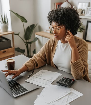 a woman sitting at a desk with a laptop and a calculator