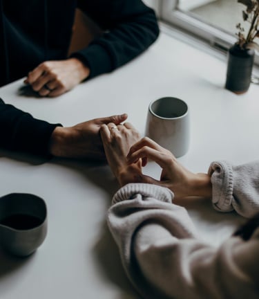 a couple holding hands over a cup of coffee