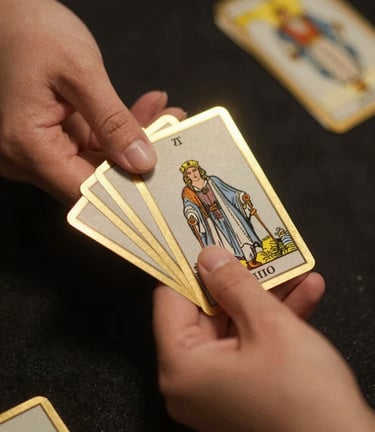 Macro close-up of elegant hands holding gold-rimmed tarot cards over a dark textured table, soft warm champagne gold light halo, 35mm lens, dark moody editorial photography