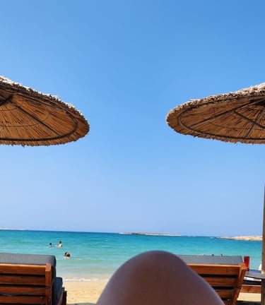 a person's feet in the sand near a beach