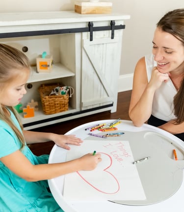 A therapist and child working on an art project titled "things I love.." 