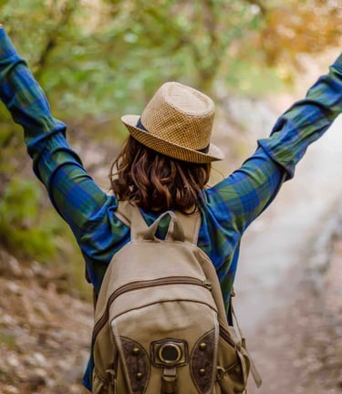 Frau mit Rucksack streckt Arme im Wald – Lebensfreude und neue Perspektiven durch Hypnose“