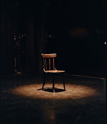 Cinematic film photography of a dark theatre stage, warm amber spotlight hitting an empty wooden chair, deep shadows, 35mm anamorphic lens