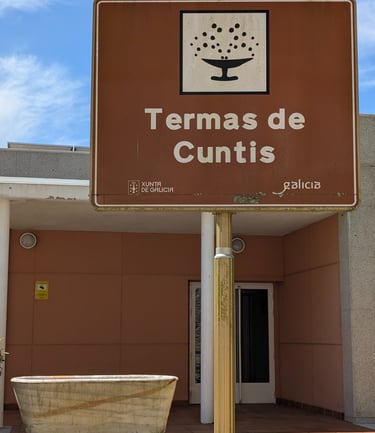 a sign that says Termas de Cunits with a marble bathtub next to it