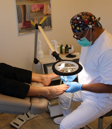 Podiatrist using a magnifying lamp and medical drill for a professional pedicure and foot treatment.